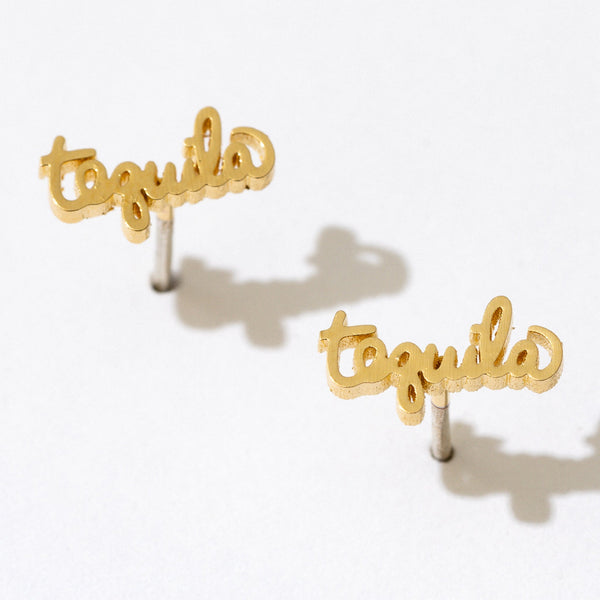 Gold Tequila Script Stud Earrings by Larissa Loden against a white background, casting a shadow.