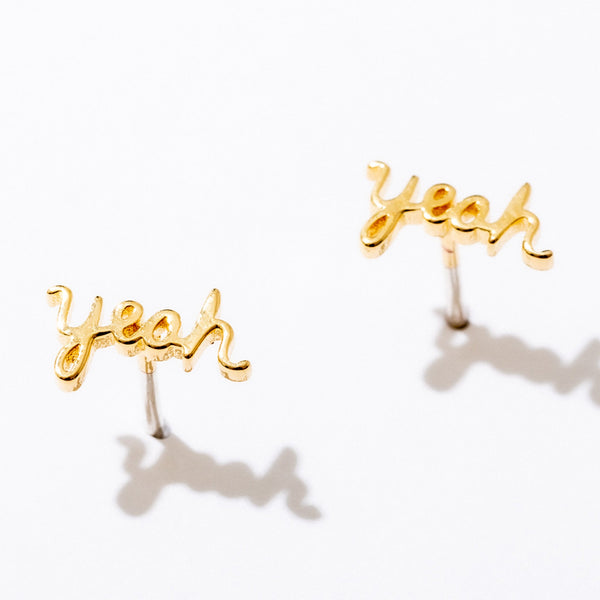 Gold Yeah Script Stud Earrings by Larissa Loden against a white background